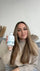 Schöne Frau mit einer Flasche Colinea Inner Radiance in der Hand die sie lächelnd in die Kamera zeigt